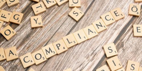 pexels-photo-19825346-19825346 Wooden letter tiles forming the word 'COMPLIANCE' on a rustic wooden background.