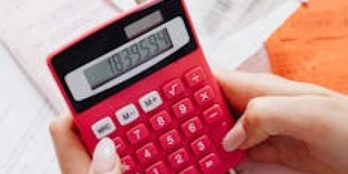 pexels-photo-7680743-7680743 A person calculating finances on a red calculator surrounded by documents.