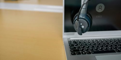 pexels-photo-8866719-8866719 Close-up of wireless headset on laptop screen, ideal for communication tech visuals.